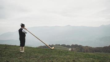 Playing the alpine horn in front of a valley in the Alps photo