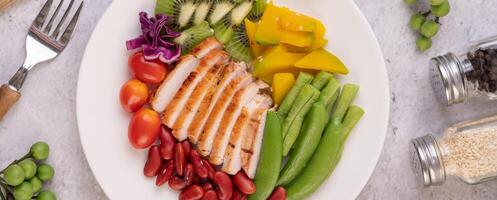 Chicken steak with peas, tomatoes, kiwi and pumpkin. photo