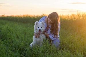 portrait of woman and white puppy of husky dog in the fields photo