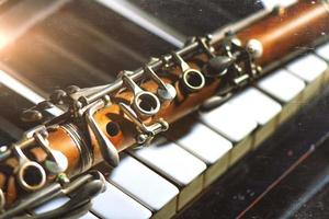 Vintage effect photograph. Antique clarinet leaning on piano keyboard photo