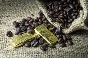 Coffee beans and Gold Bullion in sackcloth bag on wooden background photo