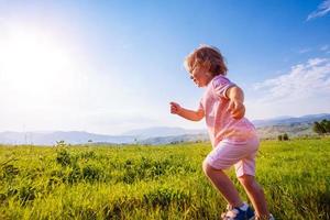 Little toddler girl running in a beautiful field photo