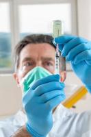 The doctor fills a syringe with vaccine on blurred background. photo