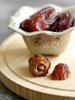 Eye angle view of Medjool dates in small silver Turkish bowl on wooden  cutting board photo