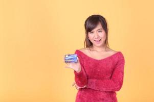una hermosa mujer asiática está feliz y piensa que gastará muchas de sus tarjetas de crédito