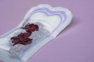Menstrual blood on a sanitary pad on pink background. Flat lay photo