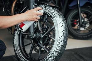 Man washing motorcycle or scooter and spraying snow foam on   Tyre wheels .Tyre restoration maintenance ,repair motorcycle concept in garage .selective focus photo