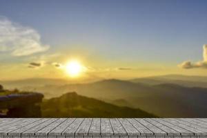 Wooden table and blur of beauty, sunset sky, and mountains as background. photo