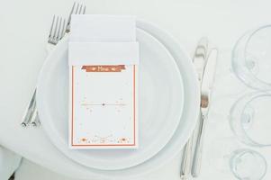 Round dinner tables covered with blue cloth stand in a white wedding pavilion photo