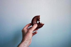 hand with a chocolate doughnut photo