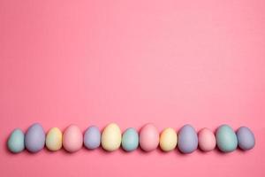 fila de huevos de pascua de color pastel sobre un fondo rosa foto