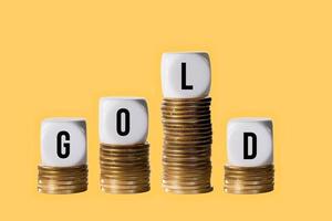 Stacks of gold coins with cubes spelling GOLD to show fall in value of the metal photo