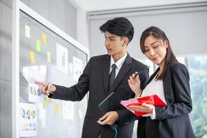 gente de negocios que se reúne en la oficina y usa notas post-it para compartir ideas. empresario y empresaria poniendo notas adhesivas de colores en la ventana de cristal en la oficina. foto