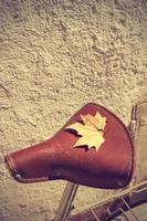 Autumn leaf over the saddle of an old bike. Vintage style. Concept arrival autumn. Vertical image. photo