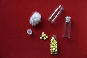 Glass vials with pills on a red background photo