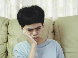 el niño pequeño de asia sufre de dolor de muelas. él triste con dolor de dientes, enfermedad dental, niño que sufre de problemas dentales. plan de cita con el dentista. foto