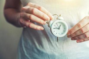 Female woman hands holding ringing twin bell vintage classic alarm clock photo