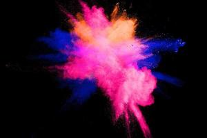 Abstract multicolored powder explosion on black background. Color dust particle splattered on background. photo