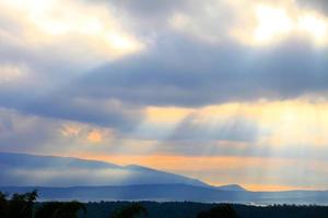 Ray of beautiful sun light shines through the cloud over the mountain photo