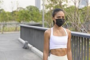 Young fitness woman in sportswear taking face mask in while exercise in city park, Health and Lifestyles. photo