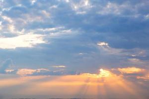 Orange rays of the sun through cumulus clouds in the sky at sunset in summer. Heavenly magic light. photo