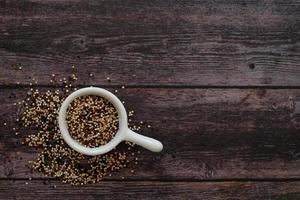 Quinoa seeds in the white cup on wooden background.  Quinoa is a good source of protein for people following a plant-based diet. photo