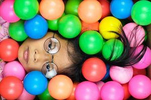 Primer plano de una niña de cara plana sobre fondo de bolas de colores foto