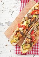 Big sandwich with roasted vegetables with cheese and thyme on old wooden background photo