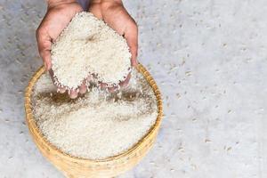 cierre el grano de arroz blanco jazmín crudo en la mano de la agricultura. foto