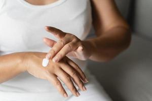 mujer aplicando crema hidratante de loción corporal en sus manos. foto