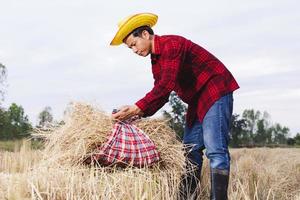 granjero asiático con rastrojo de arroz en el campo foto