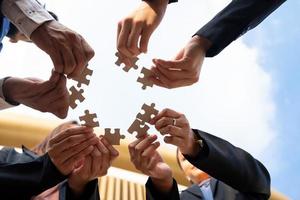 we are compatible A group of businessmen is working on puzzles together. photo