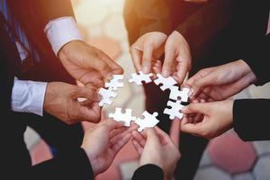 The hand of a businessman holding a paper jigsaw And solving the puzzle together. The business team assembles a jigsaw puzzle. A business group wishing to bring together the puzzle pieces photo