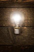 Glowing lightbulb on wooden background photo