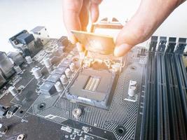 Hold the CPU handle and insert it into the CPU slot on the motherboard. It's an old motherboard, lots of dust. Put orange light on the cpu slot. There is a RAM slot next to it. There is a capacitor. photo