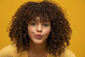 mujer afroamericana con peinado afro y maquillaje glamoroso. fondo amarillo foto