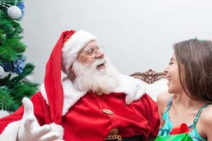 Santa Claus delivering a gift box to a little girl. Christmas eve, delivery of gifts. photo