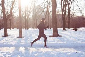 young woman athlete in black sport suit run in winter park photo