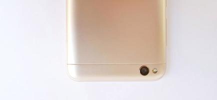 pantalla de la parte posterior de un dispositivo de teléfono inteligente de color blanco dorado con un flash LED, una sola cámara y orificios para altavoces. un diseño de vista del cuerpo de medio teléfono inteligente. adecuado para publicidad, promoción. foto