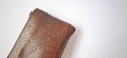 An old brown orange synthetic wallet with some money inside on the dim grey yellow background. photo