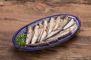 Anchovies in the bowl served basil leaves photo