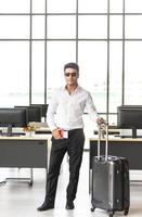 Young and smart businessman with sunglasses, suitcase and travel document such as air ticket, hotel booking document and passport with travel concept,summer vacation concept, summer holiday concept photo