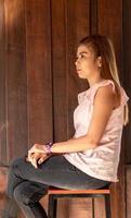 Thai woman sitting in a chair near the brown wood wall. photo