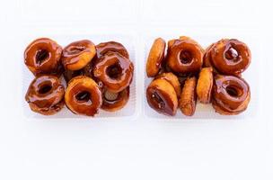 Thailand fried donuts, caramel coated in a clear plastic box on a white background. photo