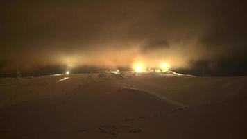 8k luzes noturnas de antenas no topo da montanha nevada no nevoeiro e nuvens video