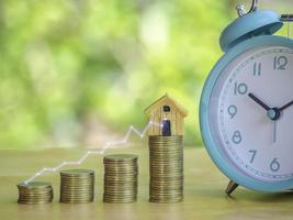 Hand are stacking coins with alarm clock to save the financial stability for the future. Concept for loan, property ladder, financial, mortgage, real estate investment, taxes and bonus. photo