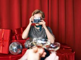 mujer alegre y hermosa fotógrafa en la celebración de la fiesta con fondo de cortinas rojas. profesión, concepto de fiesta foto