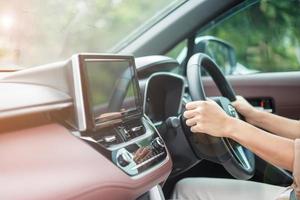 mujer conductora conduciendo un automóvil en la carretera, controlando a mano el volante en un automóvil eléctrico moderno. conceptos de transporte de viaje, viaje y seguridad foto