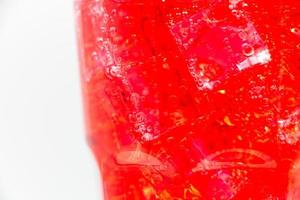 Red sparkling water with Ice in glass over white background. photo