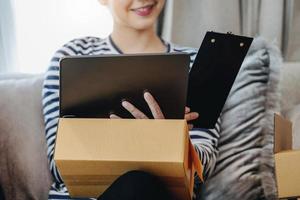 Online merchandising business idea, beautiful girl using ipad to check orders to deliver parcels to customers according to orders received from customers. photo